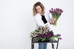 une sucré fille collecté une bouquet de différent variétés de tulipes. des stands sur une blanc Contexte photo