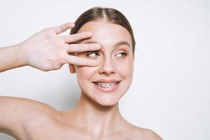 portrait de beauté d'une drôle de jeune fille à la peau fraîche, adolescente avec des accolades sur les dents sur fond blanc isolé photo