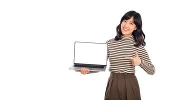 magnifique Jeune asiatique femme sur chandail tissu montrer du doigt indice doigt sur portable PC ordinateur et à la recherche à caméra avec sourire visage et content isolé sur blanc Contexte photo