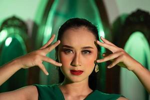 une sorcière femme avec une vert écharpe et une visage plein de magnifique maquillage a très tranchant et effrayant yeux photo