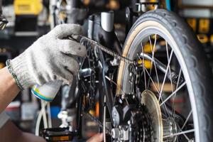 mécanicien réparer vélo, chaîne lubrifier vaporisateur pour pliant vélo travail dans atelier , vélo réparation et entretien concept photo