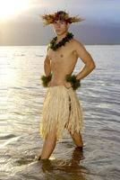 Beau Masculin hula Danseur des stands dans le l'eau comme le Soleil ensembles. photo