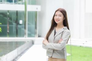 asiatique affaires travail femme avec longue cheveux dans crème costume sourit Heureusement et bras traversée à présente quelque chose à aller en dehors réunion avec clients à le bureau, travail de nulle part concept. photo