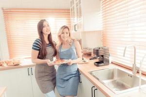 une content Jeune lesbienne couple en portant une Pizza dans le cuisine. le concept de fait maison nourriture et lgbt des relations. famille et la diversité concept. lgbt. chaud Ton. photo