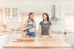 content même sexe couple alimentation chaque autre à cuisine. de bonne humeur lgbtq lesbienne femme alimentation salade chaque autre. une magnifique couple de lesbienne Dames ayant une romantique moment dans le cuisine. chaud Ton. photo