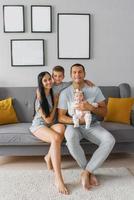 content famille avec deux les enfants sont séance sur le canapé dans leur maison et souriant photo