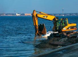 Dniepropetrovsk, Ukraine - 26.11.2021 excavatrice travaux à renforcer le digue. hydraulique excavatrice travail sur le rivière banque. photo