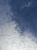 nuages blancs dans le ciel bleu. beau fond bleu clair. peu nuageux, beau temps. nuages bouclés par une journée ensoleillée. photo