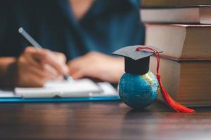 l'obtention du diplôme casquette avec Terre globe. concept de global affaires étude, à l'étranger éducatif, retour à école. éducation dans global monde, étude à l'étranger affaires dans les universités dans mondial. Langue étude photo