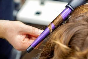 coiffeur fait du coiffure par curling le fer photo