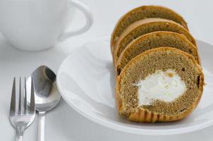 café crème rouleau gâteau avec une tasse de thé sur thé rupture temps photo