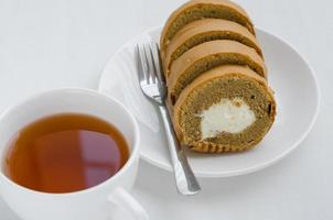 café crème rouleau gâteau avec une tasse de thé sur thé rupture temps photo