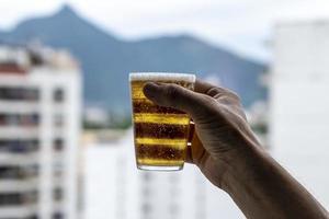 homme tenant un verre de bière sur fond de ville urbaine floue photo