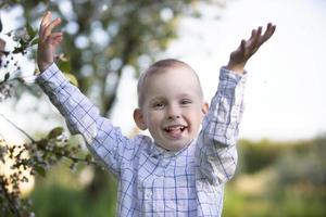 un enfant heureux dans un jardin printanier fleuri se réjouit, sourit. photo