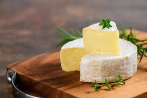 tranché Camembert fromage avec thym sur bois plaque. photo