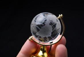 verre de cristal de globe terrestre à la main. commerce et économie mondiale. concept environnemental ou écologique photo