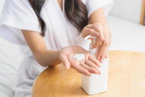 en bonne santé peau soins, beauté asiatique Jeune femme dans peignoir de bain après douche une baignoire à maison, écraser en dehors Crème hydratante de bouteille, en mettant sur sa main. peau corps crème hydratant lotion, routine dans le Matin photo