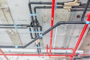 Tuyaux de ventilation en matériau isolant et gicleurs d'incendie sur tuyau rouge photo