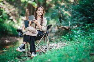 jeune femme utilise un appel vidéo sur tablette en camping dans le parc photo