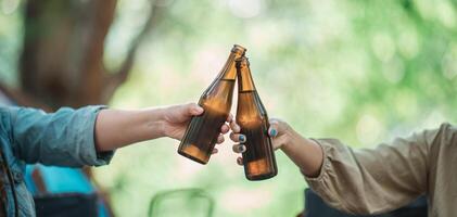 les jeunes femmes applaudissent et boivent une boisson devant la tente de camping photo