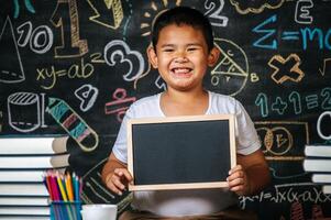 enfant debout et tenant un tableau noir dans la salle de classe photo