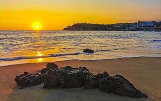 coloré d'or le coucher du soleil gros vague rochers plage puerto escondido Mexique. photo