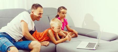 les enfants et leur père en utilisant une ordinateur portable, en ligne apprentissage à Accueil photo