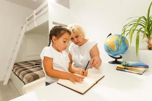 grand-mère Aidez-moi petite fille Faire école devoirs ensemble à Accueil photo