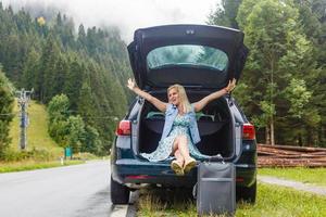 femme dans le été va sur vacances, sur vacances avec un valise sur le Contexte de la nature et montagnes. le concept de voyage, fin de semaine dans une magnifique endroit dans le montagnes photo