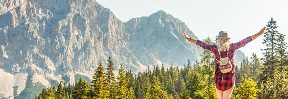 promeneur femme permanent avec mains en haut réalisation le Haut. fille se félicite une Soleil. conceptuel conception. réussi femme promeneur ouvert bras sur lever du soleil Montagne Haut. fille dans longue blanc robe dans le montagnes. photo