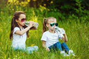 petit les enfants rafraîchissant se avec l'eau dans le parc. peu fille en buvant l'eau forme une bouteille dans le ville. photo