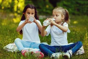 deux peu les filles sont en buvant une bouteille de l'eau dans le parc. concept de pureté, écologique et biologique produit photo