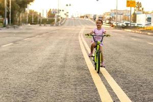 mignonne peu fille apprentissage balade une vélo. printemps été l'automne actif sport loisir pour enfants. bambin enfant sur bicyclette photo