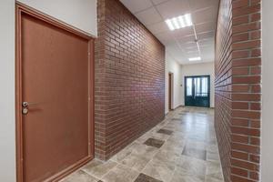 blanc vide longue couloir avec rouge brique des murs dans intérieur de moderne appartements, Bureau ou clinique photo