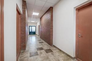 blanc vide longue couloir avec rouge brique des murs dans intérieur de moderne appartements, Bureau ou clinique photo