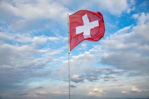 Suisse drapeau soufflant dans le vent, le Contexte est une nuageux ciel photo