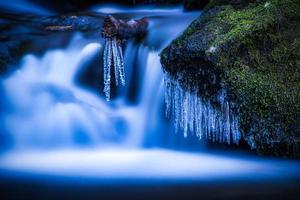 une petit cascade où une bâton des bâtons en dehors de lequel glaçons pendre photo