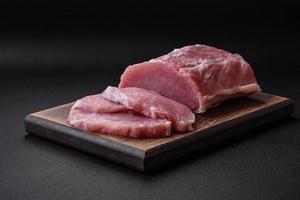 Frais juteux porc sur une en bois Coupe planche avec épices et sel photo