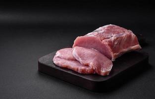 Frais juteux porc sur une en bois Coupe planche avec épices et sel photo