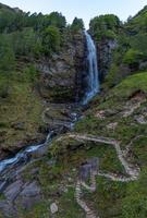 une haute cascade entouré par grand herbe et une randonnée Piste photo