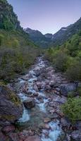 une courant avec grand rochers cette court entre montagnes et des arbres photo