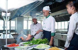 Jeune chef, Université professeur est qui passe sur le connaissance de cuisine à élèves photo