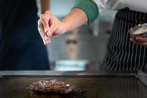 professionnel chef qui se spécialise dans bien viandes le steak cette est servi à le client est incontestablement délicieux. un autre doit avoir pointe est saupoudrage sel. photo