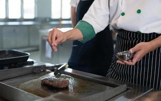 professionnel chef qui se spécialise dans bien viandes le steak cette est servi à le client est incontestablement délicieux. un autre doit avoir pointe est saupoudrage sel. photo