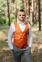 portrait de le jeune marié dans une gris costume et un Orange gilet photo