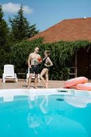 gars et une fille dans baignade costume sont relaxant, près le bleu bassin photo