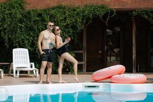 gars et une fille dans baignade costume sont relaxant, près le bleu bassin photo