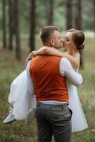 Jeune couple la mariée dans une blanc court robe et jeune marié dans une gris costume dans une pin forêt photo