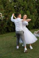 le premier Danse de le jeune marié et la mariée dans une court mariage robe sur une vert Prairie photo
