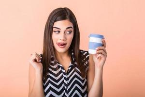 café amoureux concept. fermer photo portrait de délicieux de bonne humeur positif avec à pleines dents radieux sourire la personne en portant tasse de chaud latté dans mains et lécher sa lèvre isolé brillant Couleur Contexte